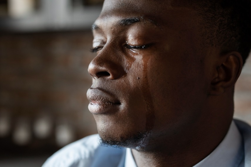 A yound African male crying with tears rolling down his cheeks.